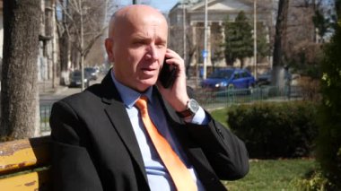 El hareketi işadamı-cep telefonunuza konuşan bankta otururken hayal kırıklığına