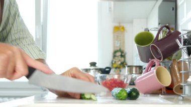 Mutfak kesme bıçağı kullanarak erkekte yuvarlak taze salatalık dilimleri Vegan diyet için
