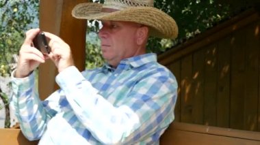 Mesaj göndermek için cep telefonu dışında bir ahşap Swinger oturan çiftçi kullanın