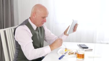 İş adamı yemek zevkli öğle ve Tablet kullanarak erişim Internet veri