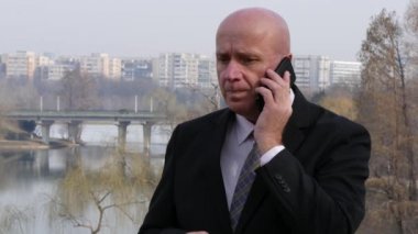 Bir toplantı dışında iş yeri bekliyorum cep telefonu için konuşan işadamı