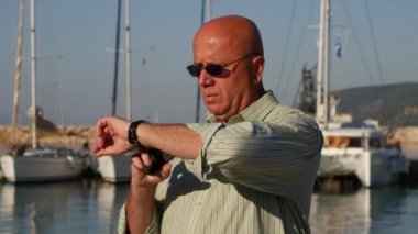 Adam güneş gözlüğü onay cep telefonu saat ve geç bir toplantı bekleyen el izle