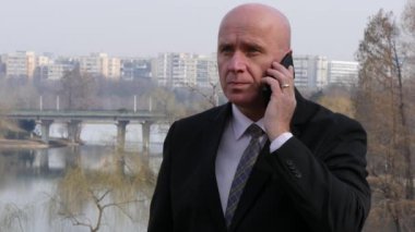 Memnun işadamı mobil konuşma gülümse ve iyi bir finansal anlaşma müzakere