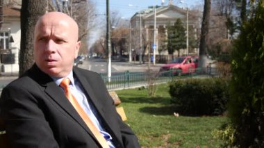 İşadamı bir Bank üzerinde bekleyin ve ortak toplantı için selam mutlu hareketleri yapmak