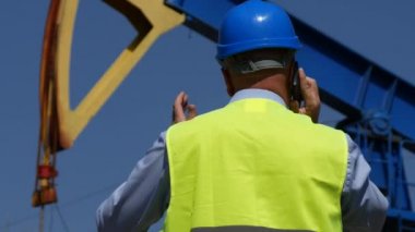 Cep telefonu bir yağ pompası önünde konuşurken petrol şirketi çalışan mühendis