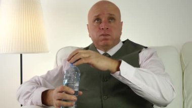 Bir şişe bir kanepe içecek soğuk tatlı su üzerinde Siting yorgun işadamı