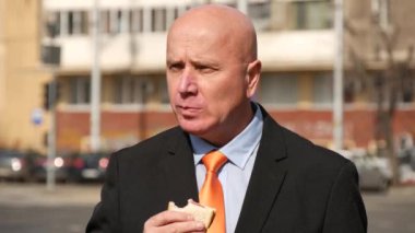 Sokakta bir toplantı bekliyor seyir sandviç yeme işadamı