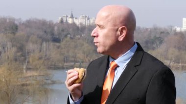 Aç işadamı öğle yemeği molası dışında ofis binası içinde lezzetli sandviç yeme.