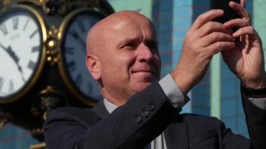 Gülümseyen ve şehir merkezi sokak üzerinde cep telefonu kullanarak filme mutlu işadamı