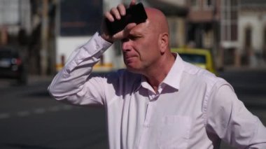 Gergin işadamı sokakta cep telefonuyla Internet ağ bulmaya çalışıyorum.