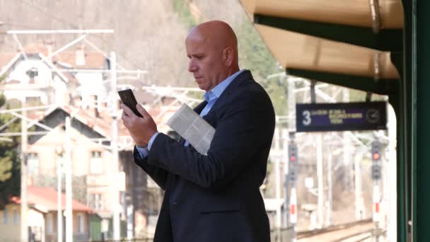 商人通勤等待火车到达和使用移动发送电子邮件 — 图库视频影像
