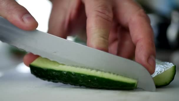 Fermer l'image avec des mains d'homme dans la cuisine coupant le concombre aromatisé en tranches fraîches — Video