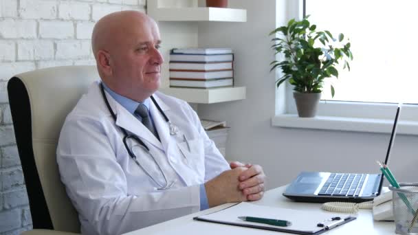 Médico complacido sonríe sentado en la silla en la oficina médica — Vídeo de stock