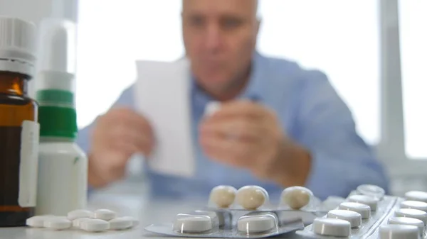 Hombre mirando a algunas píldoras con una receta médica en la mano — Foto de Stock