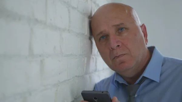 Расстроенный бизнесмен думает, что разочарован мобильным телефоном в руке — стоковое фото