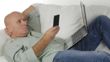 Kanepe kullanım cep telefonu ve Laptop kablosuz iletişim üzerinde yatan adam