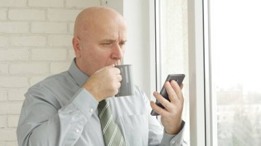İşadamı cep telefonu metin okumak ve bir fincan çay içmek