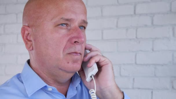 Разочарованный бизнесмен пытается позвонить по телефону, используя стационарный телефон — стоковое видео