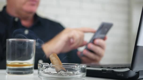 Blurred Image with Businessman Using Mobile Text and Smoking a Cigar — Stock Video