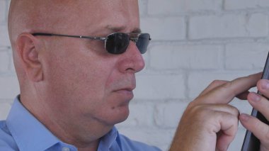 Akıllı telefon iletişim kullanarak güneş gözlüğü metin giyen işadamı