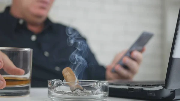 Blurred Image with a Businessman Smoking Cigar Drinking Whisky and Using Cellpho — Stock Photo, Image