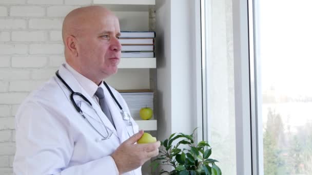 Голодный врач в медицинской клинике ест свежее яблоко — стоковое видео
