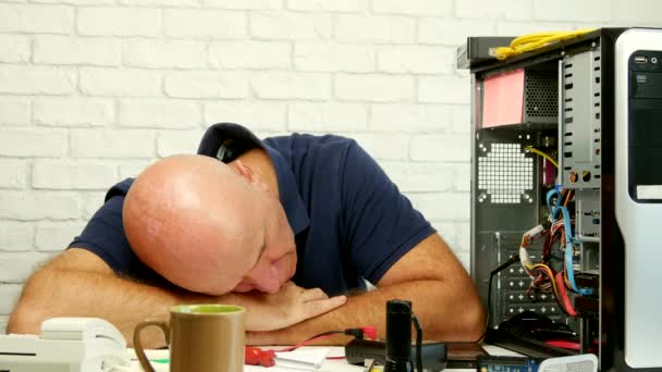 Técnico cansado durmiendo sobre la mesa en un servicio informático — Vídeos de Stock