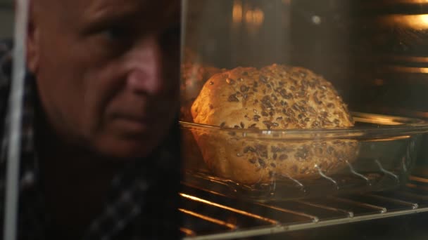 Imagem borrada do homem refletida no vidro do forno olhando para o pão — Vídeo de Stock