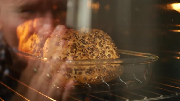 Человек размытое изображение отражается в печи стекло выглядит счастливым, чтобы хлеб протирая руки — стоковое видео