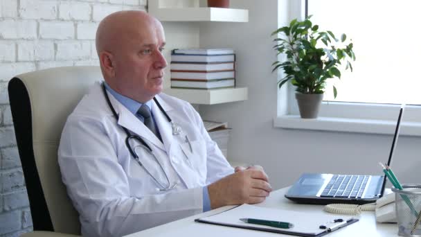 Imagen del doctor en el gabinete del hospital Espere a un paciente sentado en su escritorio — Vídeos de Stock