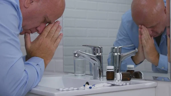 Suffering and Disappointed Person in Bathroom with Pills and Drugs on the Sink