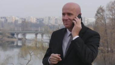 Gülümseyen ve iş Smartphone için konuşuyor işadamı ile dış ağır çekim