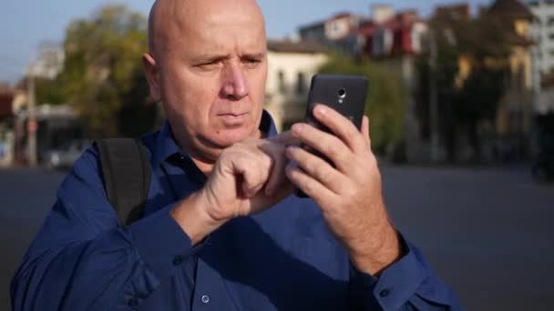 Geschäftsmann Straßentext Mit Handy Blick Die Kamera Und Selbstbewusstem Lächeln — Stockvideo