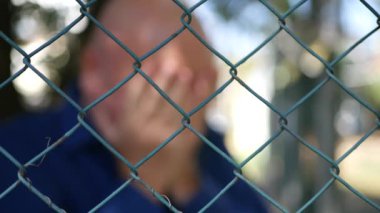 Bir metal çit arkasında bir hayal kırıklığına erkeklerle bulanık görüntü