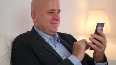 Kanepe gülümseme ve cep telefonu kullanarak metin içinde rahat işadamı kalmak