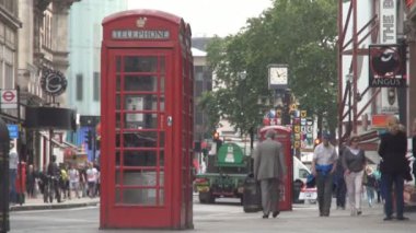 Kalabalık bir cadde üzerinde geleneksel telefon kulübesi görüntüsüyle Londra