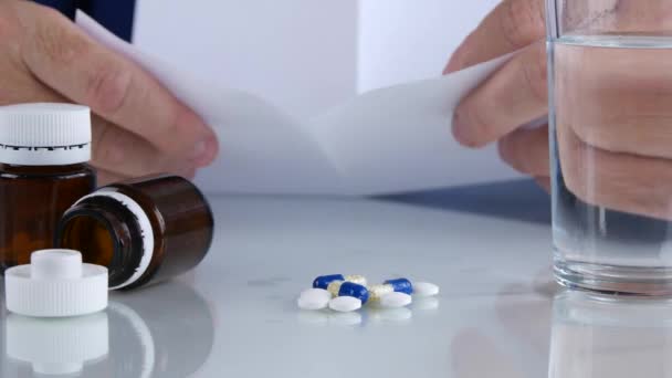 Souffrant homme lisant et vérifiant un prescription médicale avec des pilules sur la table 