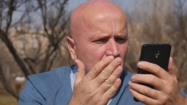 Ağır çekim üzgün adam cep telefonu kötü haber okuma ve el hareketi ile hayal kırıklığına