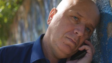 Üzgün adam sokakta bir duvarının yakınında bir telefon görüşmesi başlatmak deneyin
