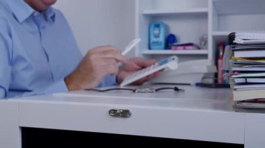 İşadamının elinde bir kalem ile hesap makinesi kullanarak hesaplamalar yapmak