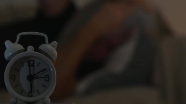 Ön planda çalar saat ile yatakta uyumak yorgun bir kişi ile bulanık görüntü