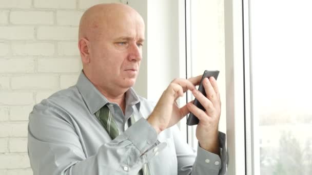 オフィスの窓の前に携帯電話を使用して非連結ネクタイ テキストを持ったビジネスマン — ストック動画
