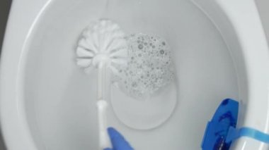 Adam eldivenli ellerinde bir fırça ve çözüm kullanarak Klozet Temizleme