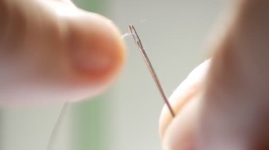 Bir iğne dikiş iplik tanıtan adam elleriyle ateş yukarıya kapatmak