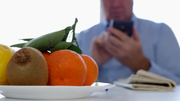 Man Met Kranten Vruchten Tekst Een Tabel Gebruiken Mobiel Communicatie — Stockvideo