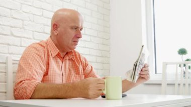 Tablo rahat üzerinde oturan kişi gazete okumak ve bir bardak kahve ile içki