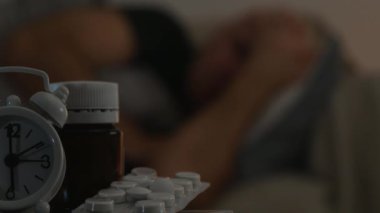 Acı adam kötü tıbbi hapları ve çalar saat ile masaya dinlenme