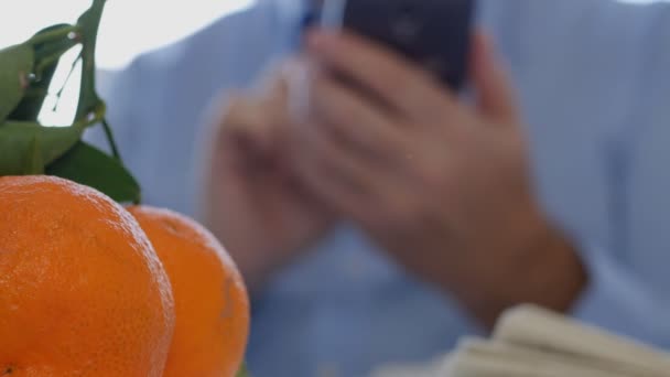 新聞やテーブル テキストに携帯電話を使用して果物を持ったビジネスマン — ストック動画