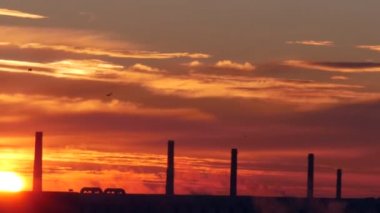 Zaman sukut ile sabah duman bulutları ile bir fabrika üzerinde kırmızı gündoğumu