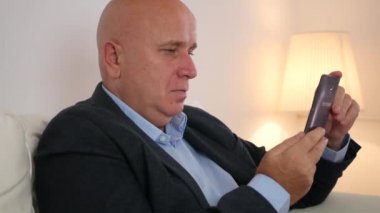 Kanepe kullanım cep telefonu ve içki alkol üzerinde oturan rahat işadamı